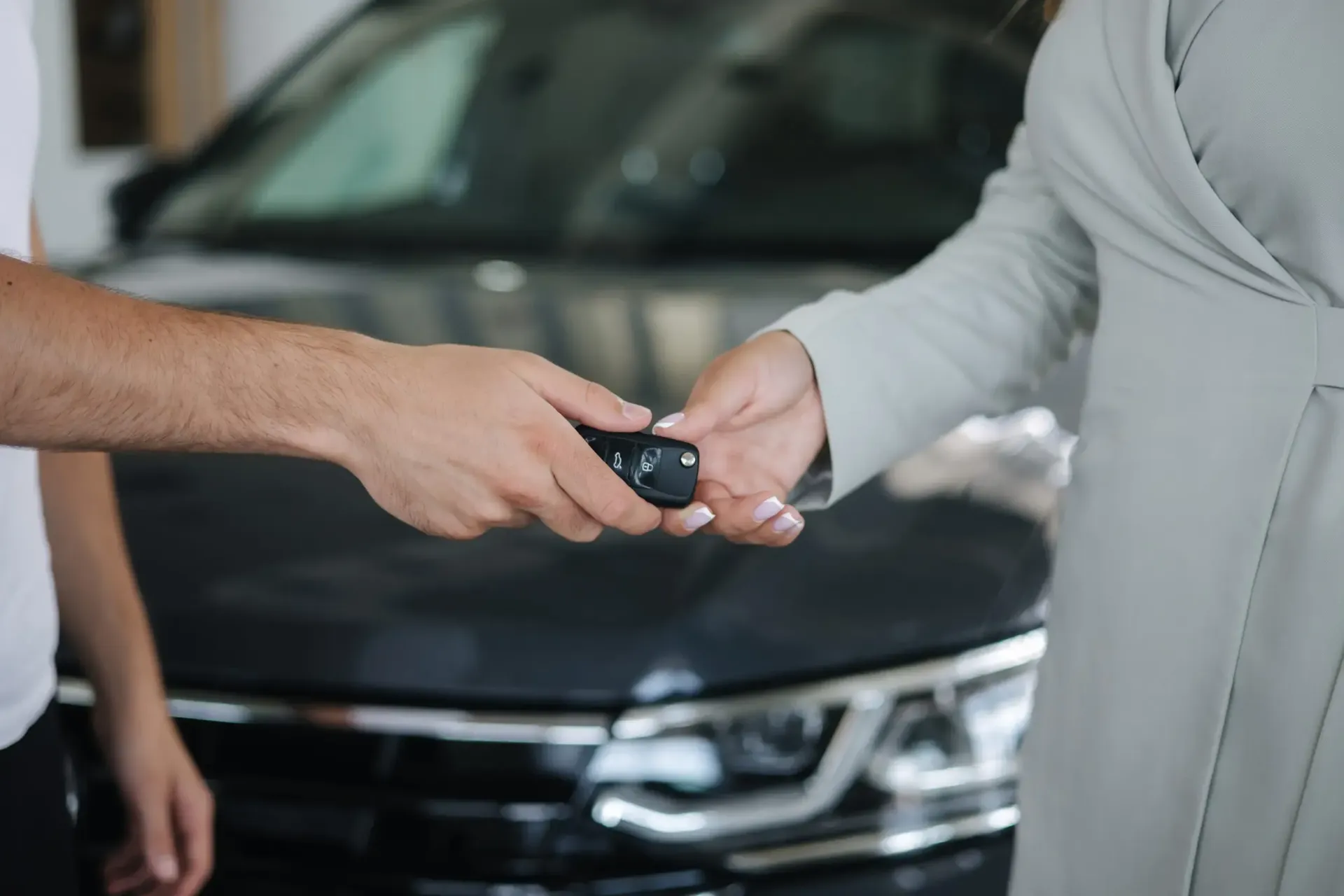 En un concesionario de automóviles, una persona le entrega el mando a distancia de un coche 