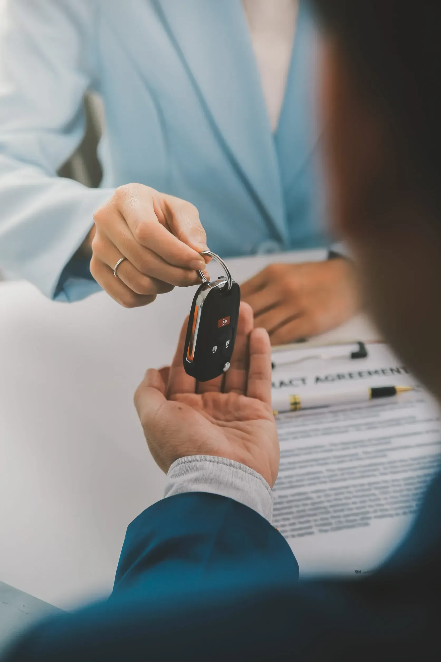 En un concesionario de automóviles, una persona le entrega el mando a distancia de un coche 