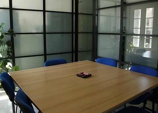 Una sala de conferencias con una mesa de madera y sillas azules.