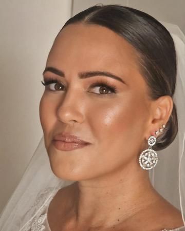 Mujer con maquillaje elegante y pendientes, que lleva un velo; mirando hacia la izquierda.