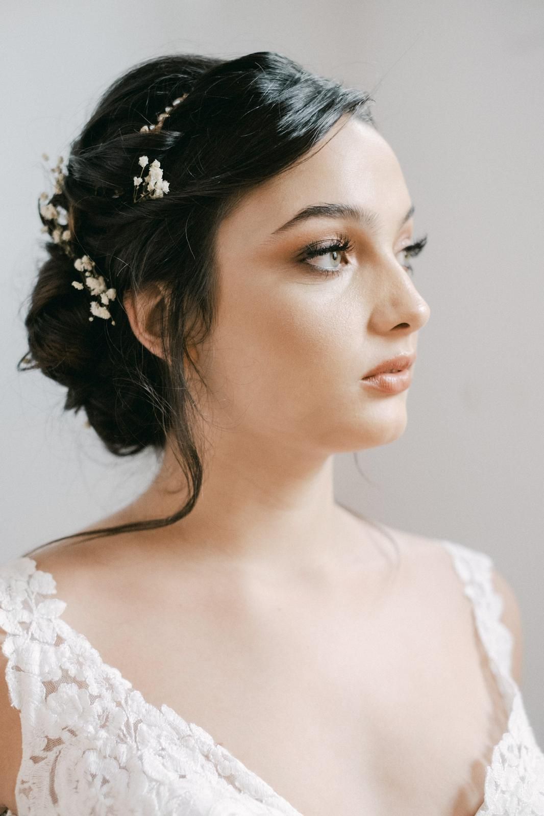 Mujer con peinado recogido, adornado con pequeñas flores blancas, que viste un vestido con detalles de encaje