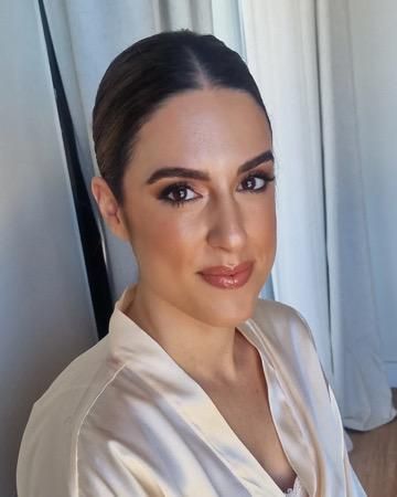 Mujer con peinado recogido y maquillaje glamuroso, vestida con una bata de satén, mirando a la cámara.