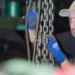 Ein Mann mit Hut und blauen Handschuhen hält eine Kette.