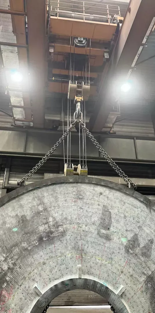 In einer Fabrik wird ein großes Stück Metall von einem Kran angehoben.