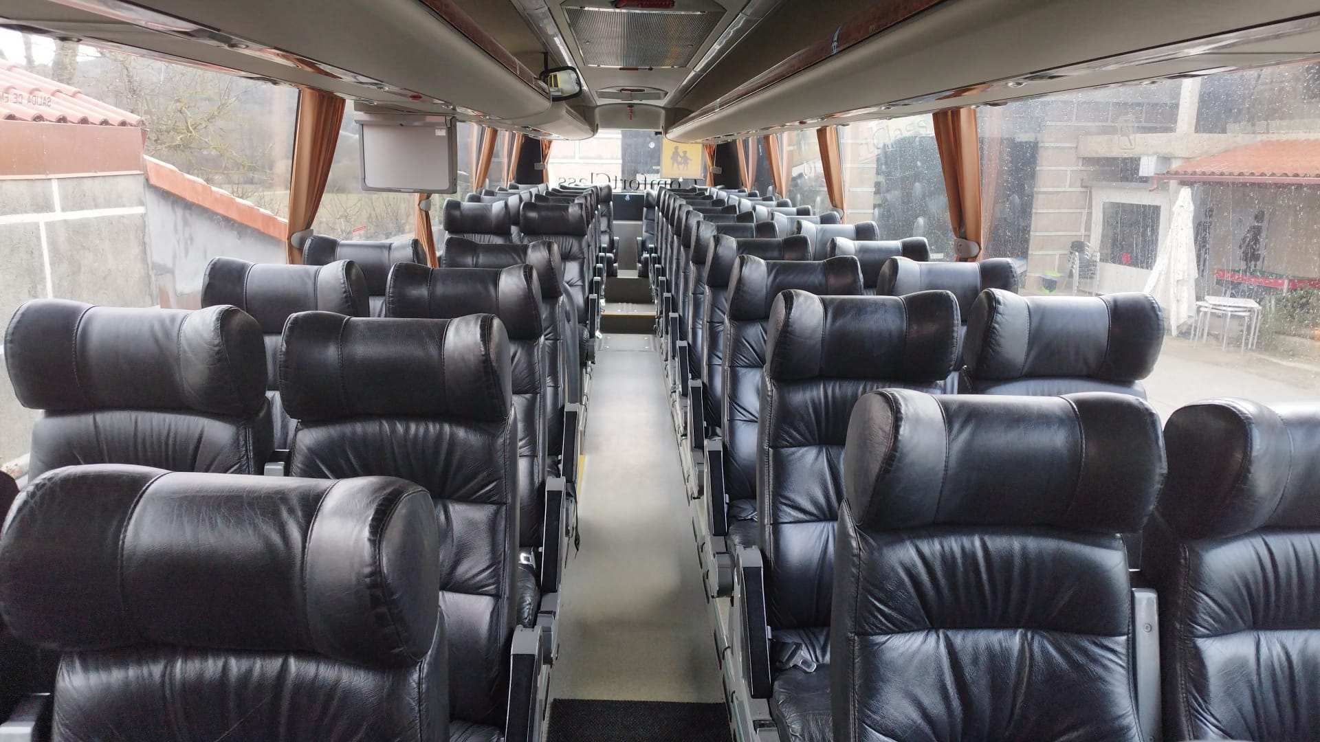 Tres autobuses turísticos y una camioneta estacionados afuera de un edificio.