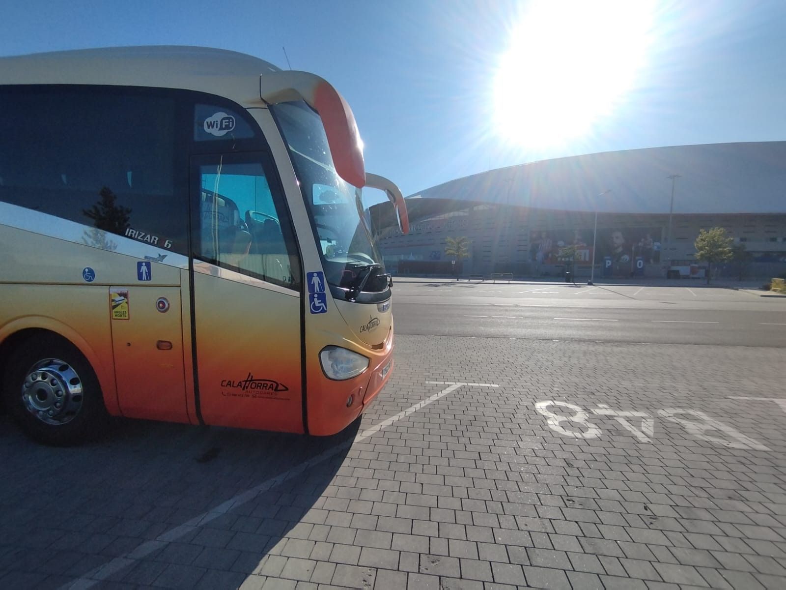 Un autobús estacionado en un aparcamiento bajo un sol radiante.