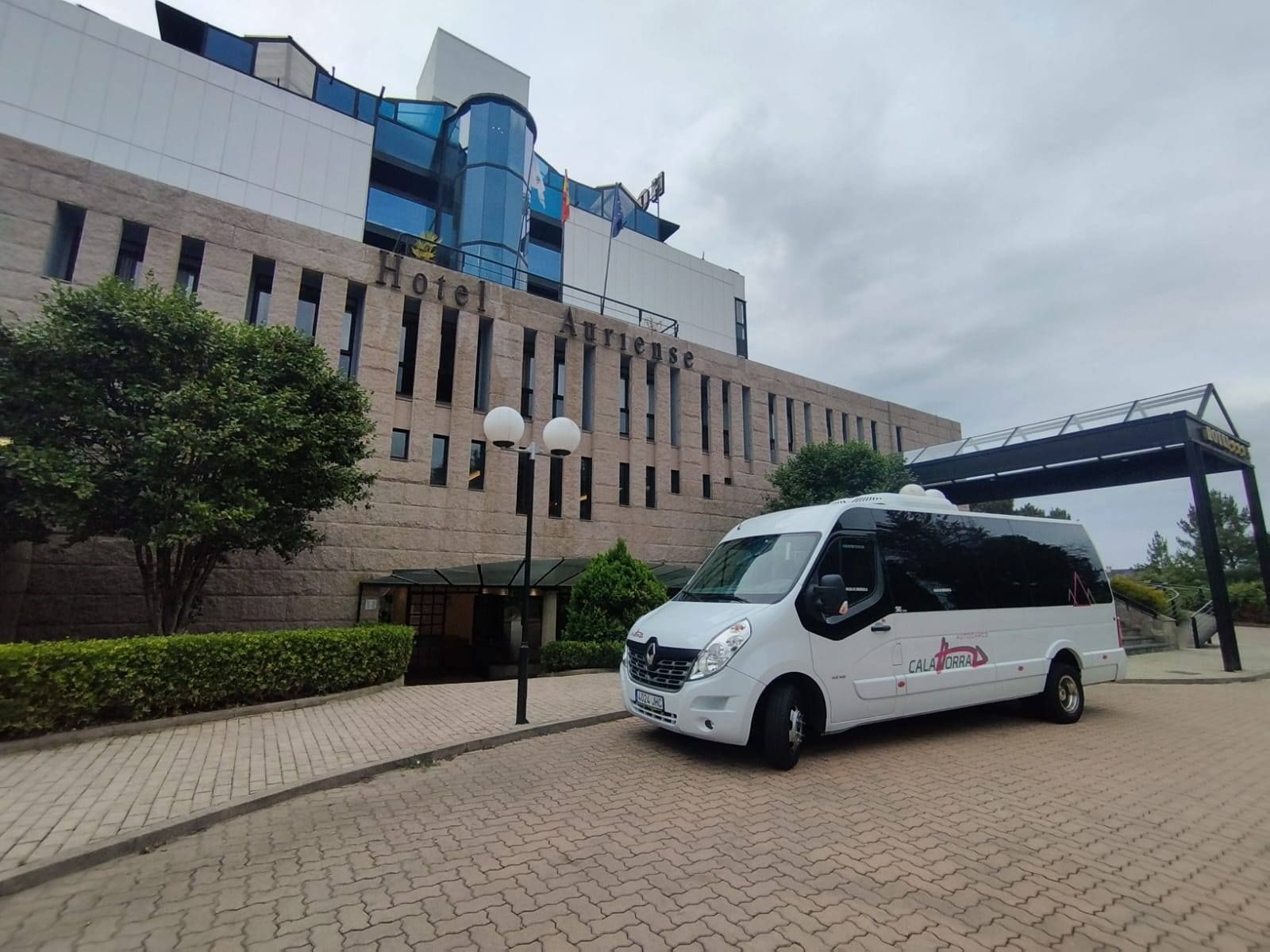 Una camioneta de pasajeros blanca estacionada frente al Hotel Ariston.