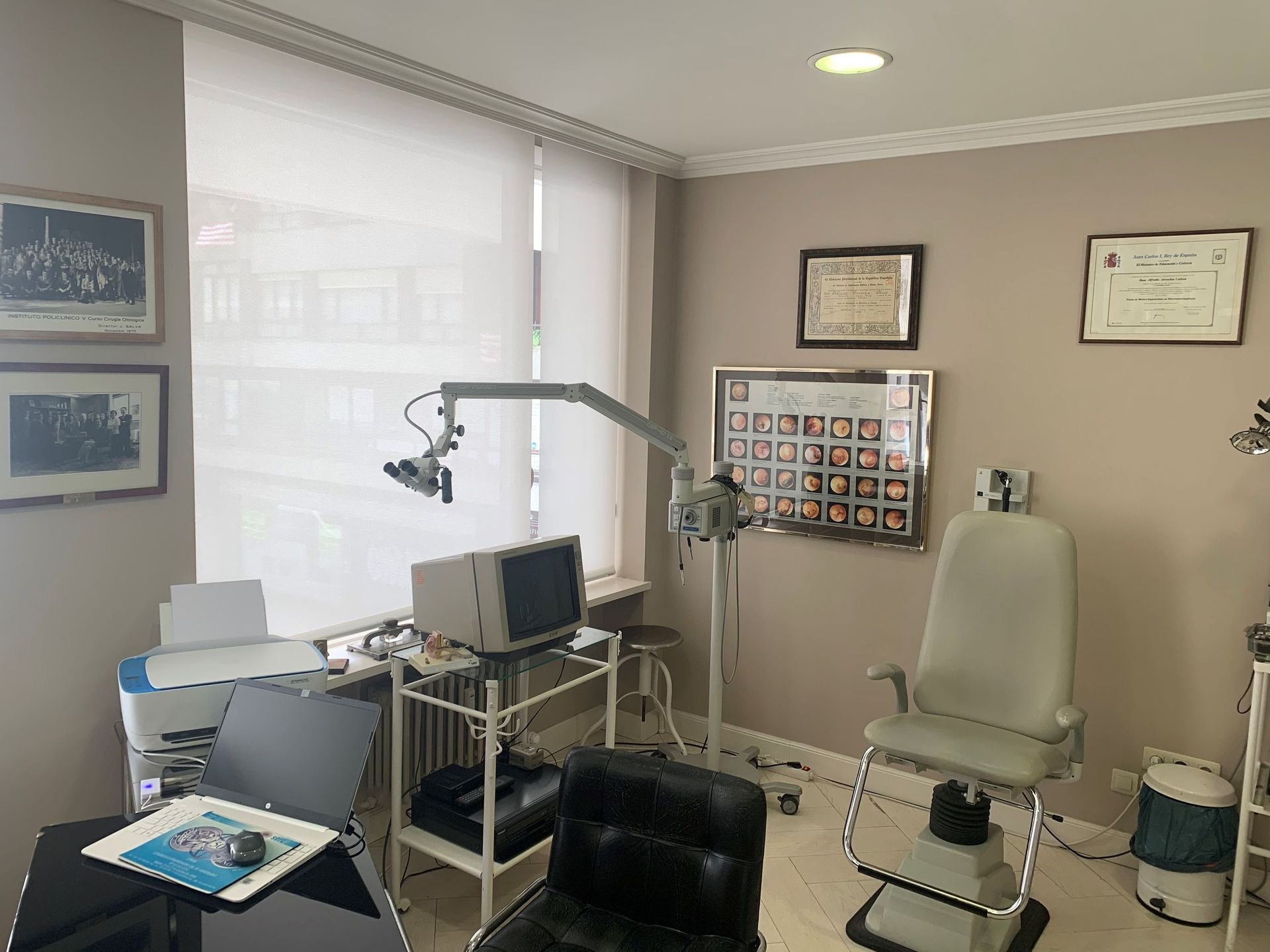 Un consultorio médico otorrinolaringólogo con una silla, equipo de exploración y un escritorio.