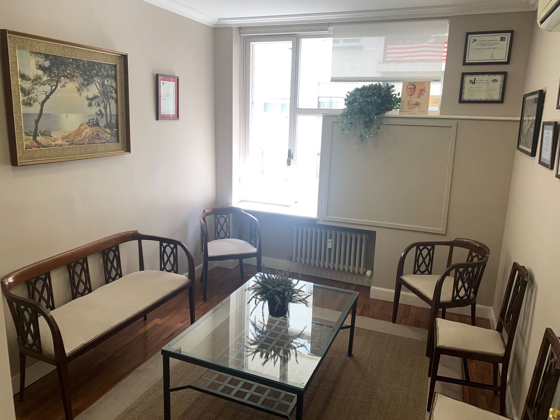 Sala de espera con muebles de madera, mesa de centro de cristal y ventana.