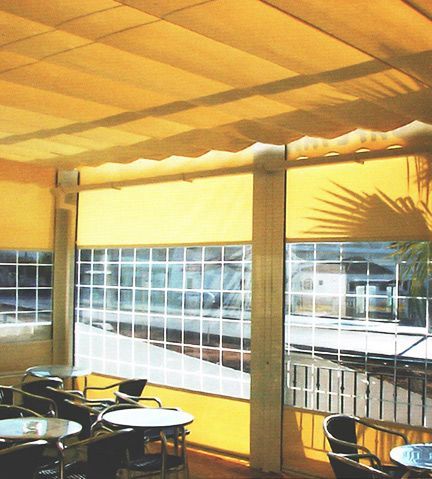 Una habitación con mesas y sillas bajo un toldo amarillo.