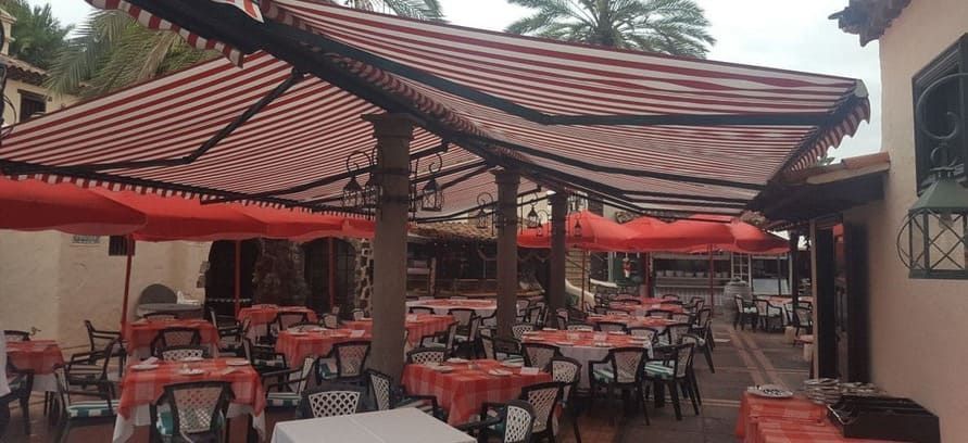 Un restaurante con mesas y sillas bajo un toldo.