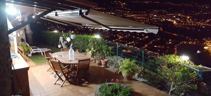 Un patio con mesa y sillas y una vista de una ciudad de noche.