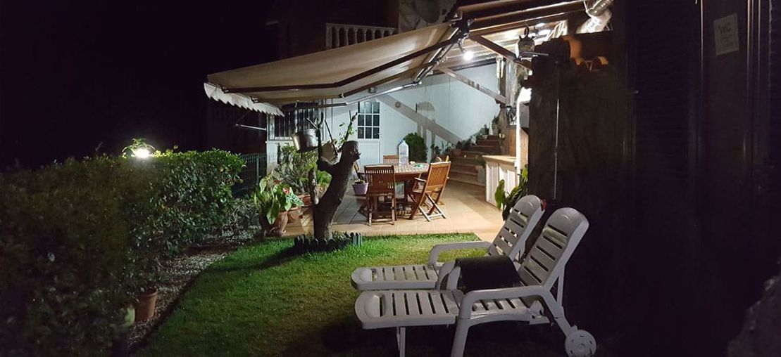 Un par de sillas están sentadas frente a una casa por la noche.