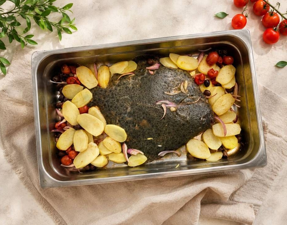 Polpo grigliato con patate arrosto e salsa verde su un piatto bianco