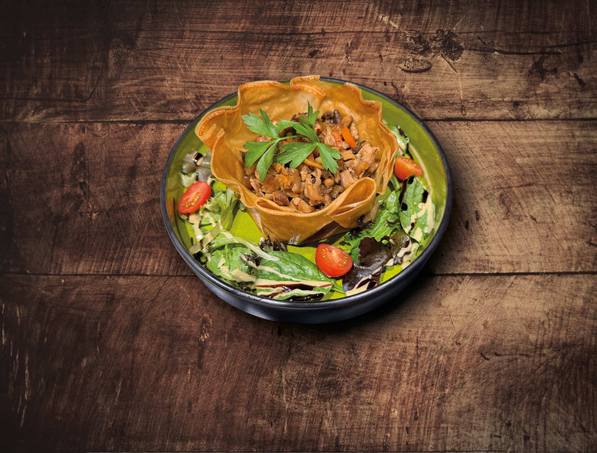 Salade dans un bol avec un panier de tortillas frites rempli de nourriture, sur une table en bois.