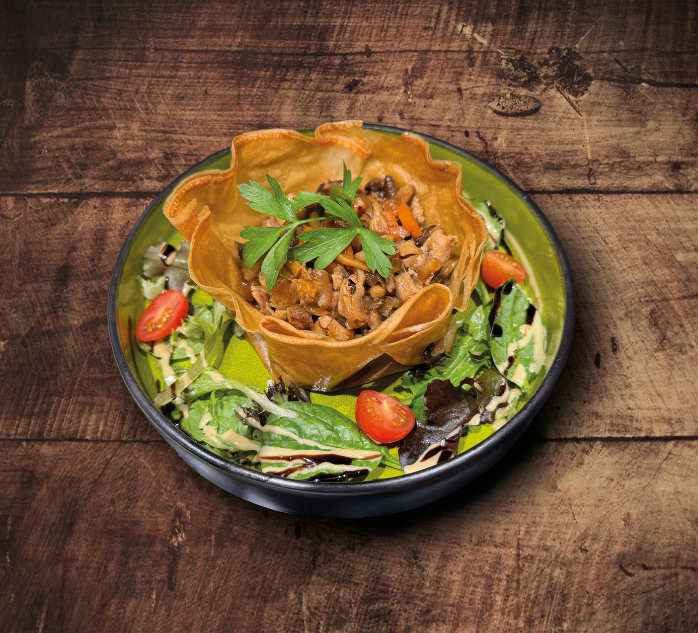 Salade avec un bol de tortilla rempli de viande, garni de persil et de tomates, sur une table en bois.