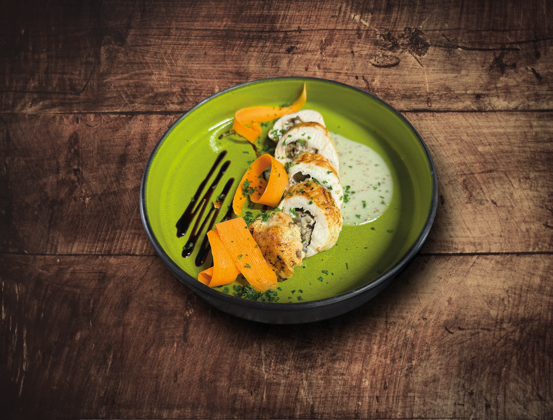 Poitrine de poulet farcie avec rubans de carottes et sauce sur une assiette verte
