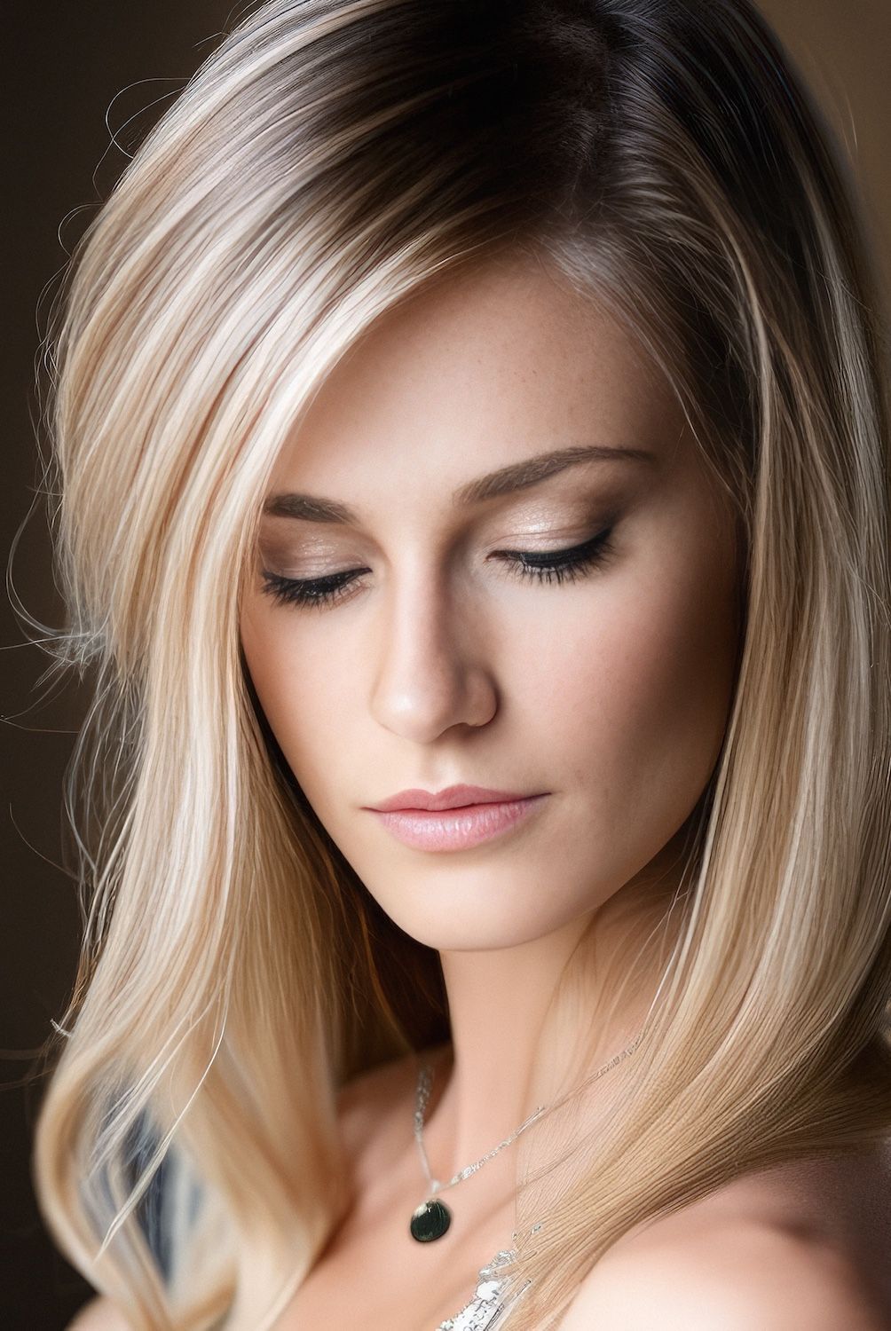 Portrait d'une femme blonde regardant vers le bas, portant un collier pendentif noir