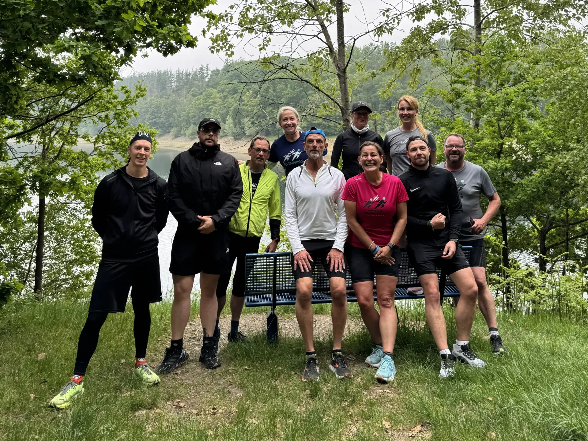 A group of people are posing for a picture in front of a lake.