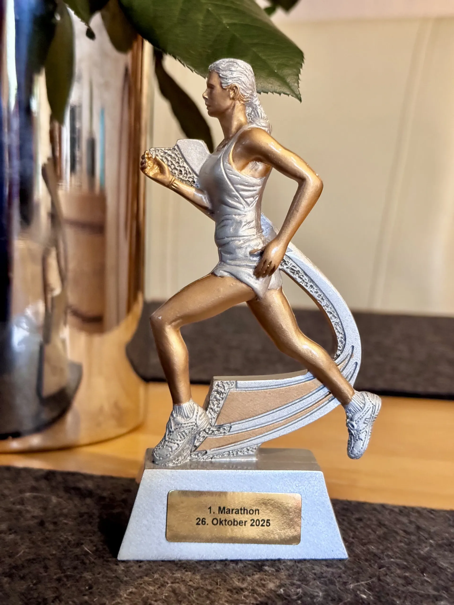 Trophäe eines Läufers in silber-goldener Kleidung, der auf einen Startblock tritt.