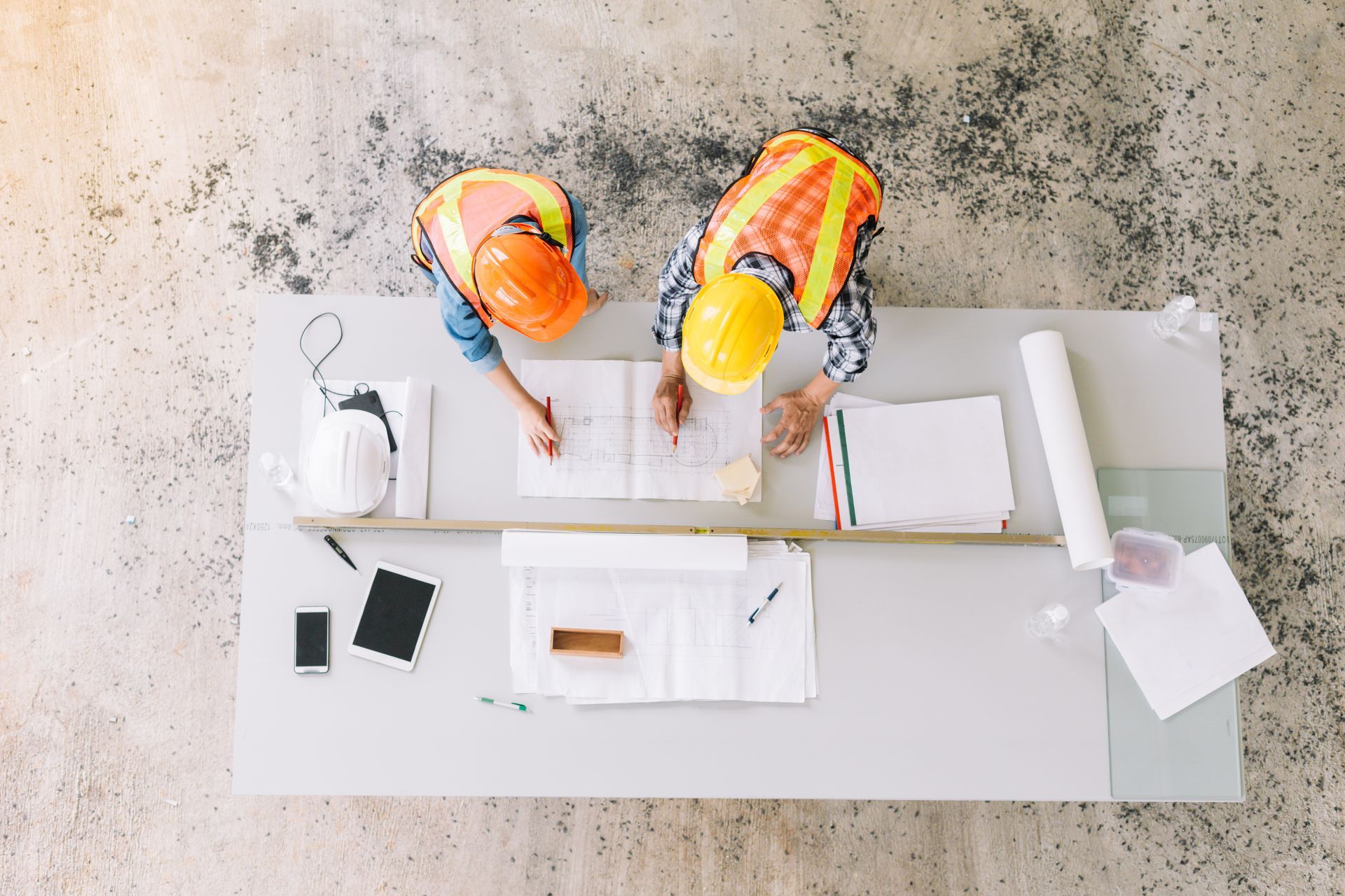 Deux hommes casqués discutant d'un plan posé sur une table