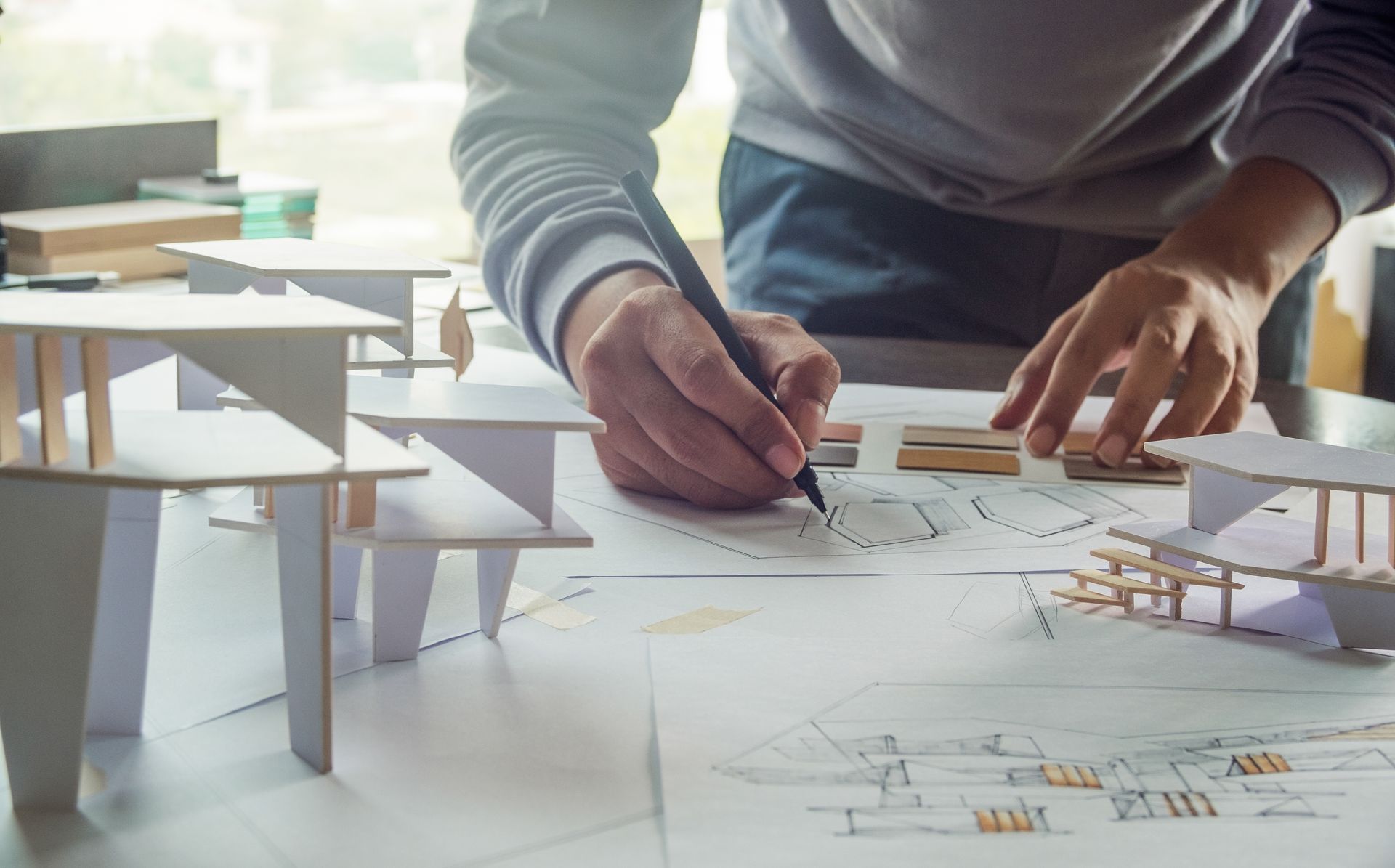 Maquette en carton d'une construction avec un architecte dessinant les plans