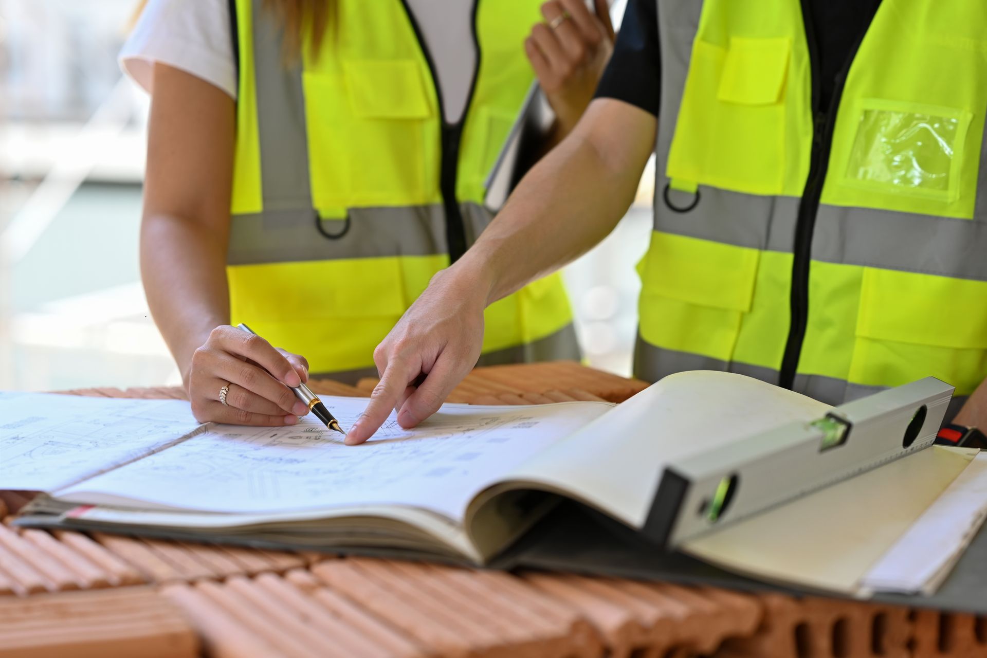 Deux personnes portant une veste de chantier consultent un plan
