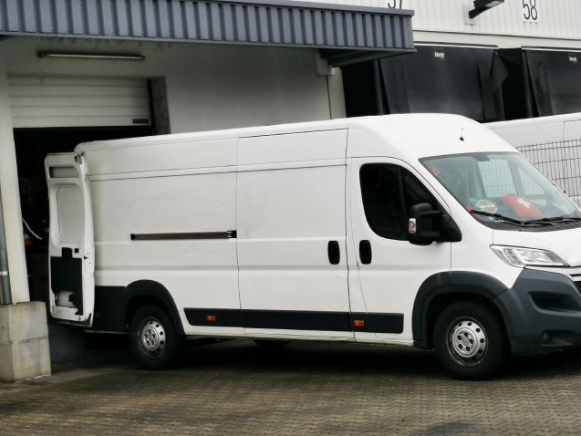 Ein weißer Lieferwagen steht vor einem Gebäude mit der Nummer 56