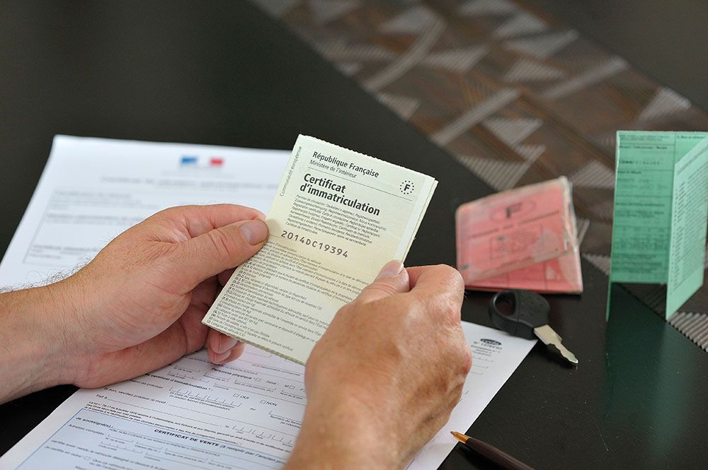 Homme tenant des deux mains la carte grise de sa voiture