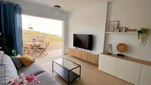 Una sala de estar con sofá, mesa y televisión.