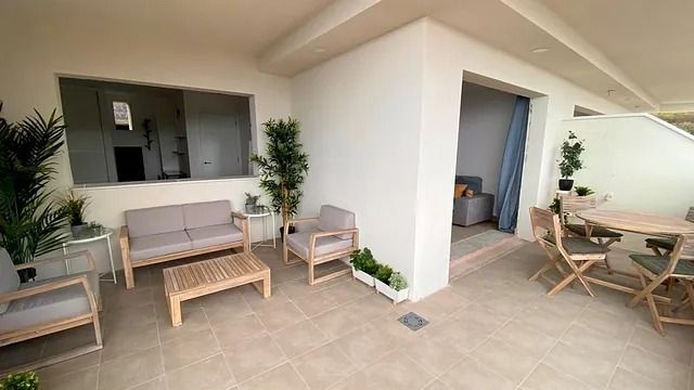 Un patio con un sofá, sillas, una mesa y una ventana.
