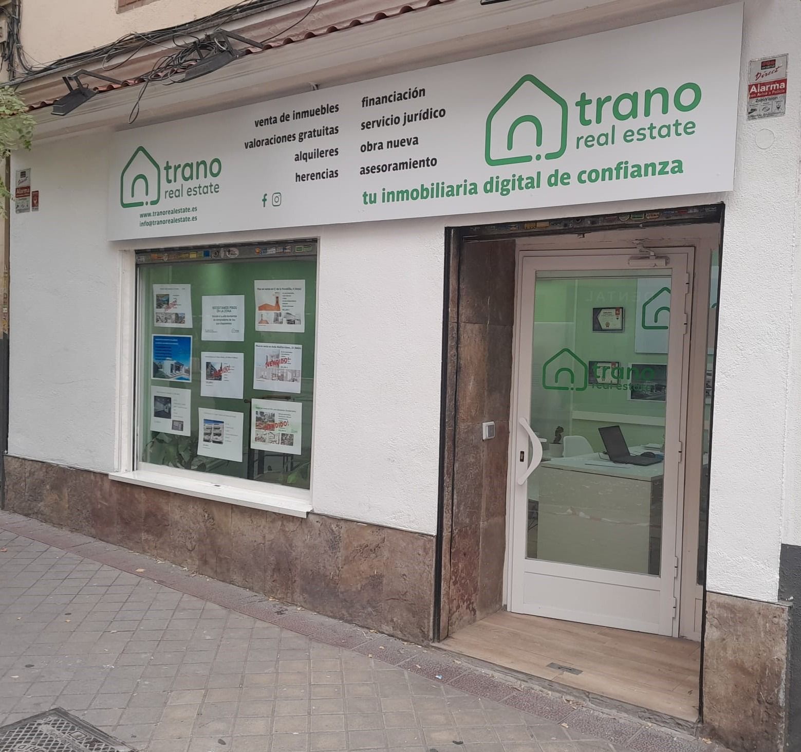 Un edificio blanco con un letrero verde que dice Trano Real Estate.