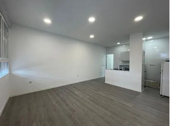 Una sala de estar vacía con pisos de madera y paredes blancas.