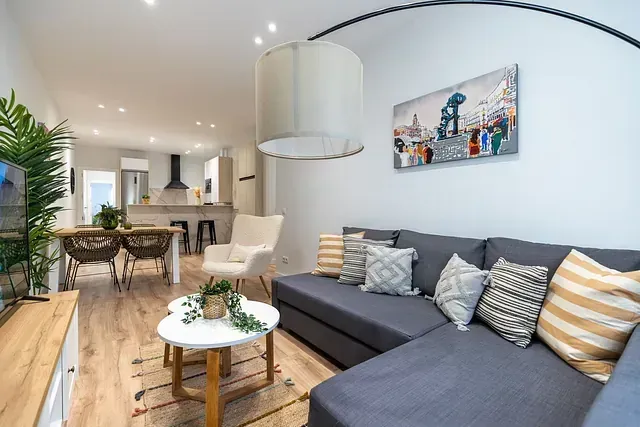Una sala de estar con un sofá, una mesa, sillas y un cuadro en la pared.