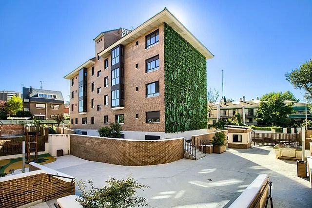 Un gran edificio de ladrillo con una pared verde a un costado.