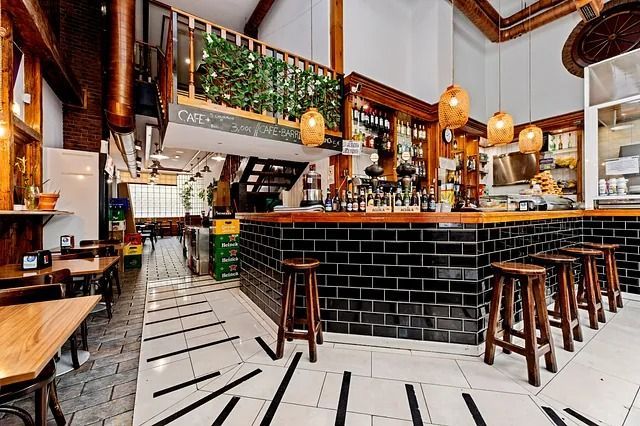 Un restaurante con barra, mesas, sillas y taburetes.