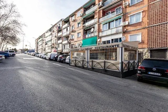 Una fila de coches están aparcados al costado de la carretera frente a un edificio.
