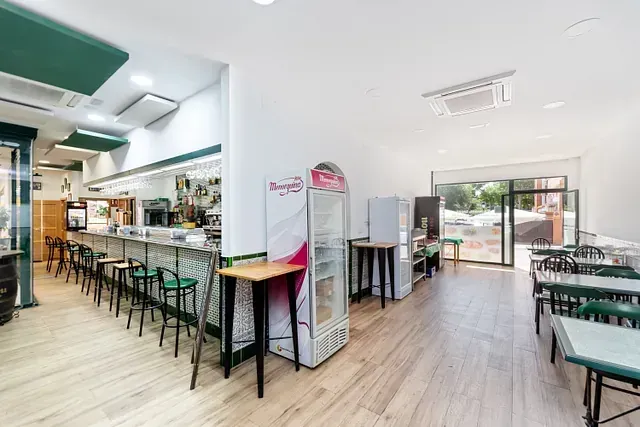 Un restaurante con mesas y sillas y un refrigerador en el medio de la habitación.