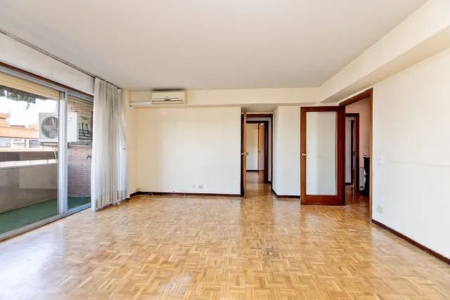 Una sala de estar vacía con pisos de madera y paredes blancas.