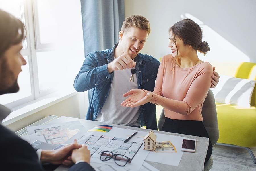 Un hombre le da una llave a una mujer mientras está sentado en una mesa.