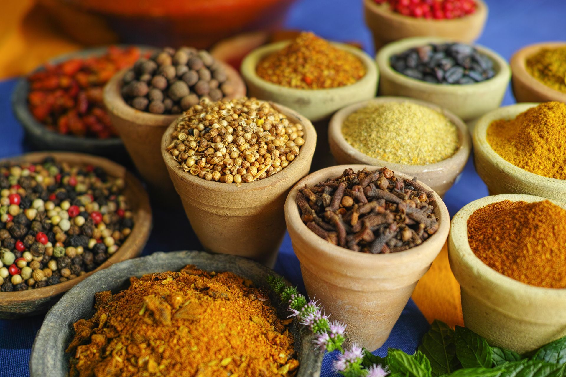 Assortiment d’épices colorées dans des bols et des cornets, présentées comme sur un étal de marché.