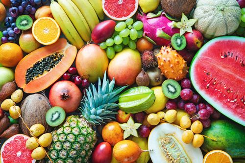 Assortiment de fruits colorés, notamment de la pastèque, de la papaye, de l’ananas, du raisin et des agrumes, disposés les uns contre les autres