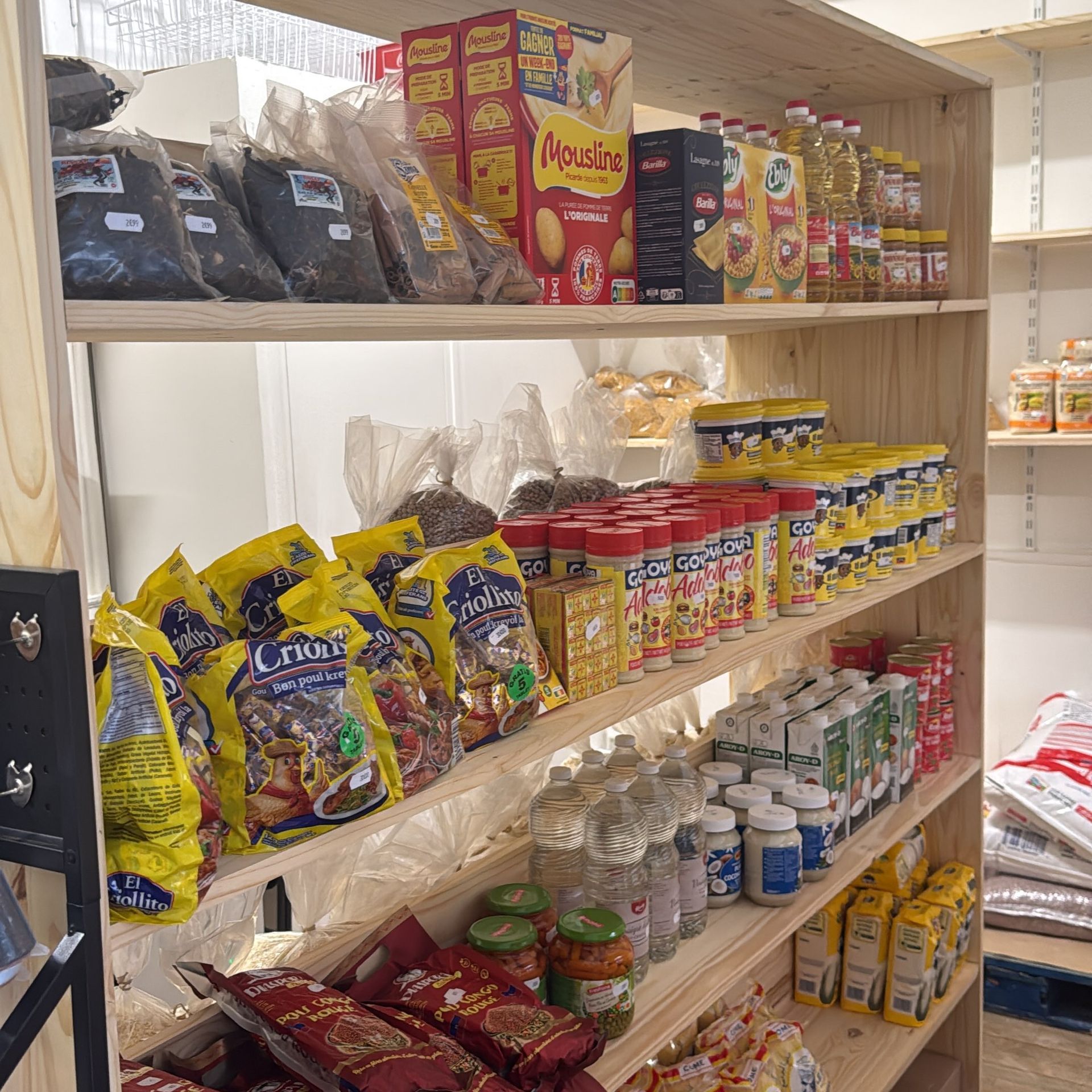 Des étagères garnies de divers snacks emballés, de bocaux et de boissons en bouteille dans une petite boutique.