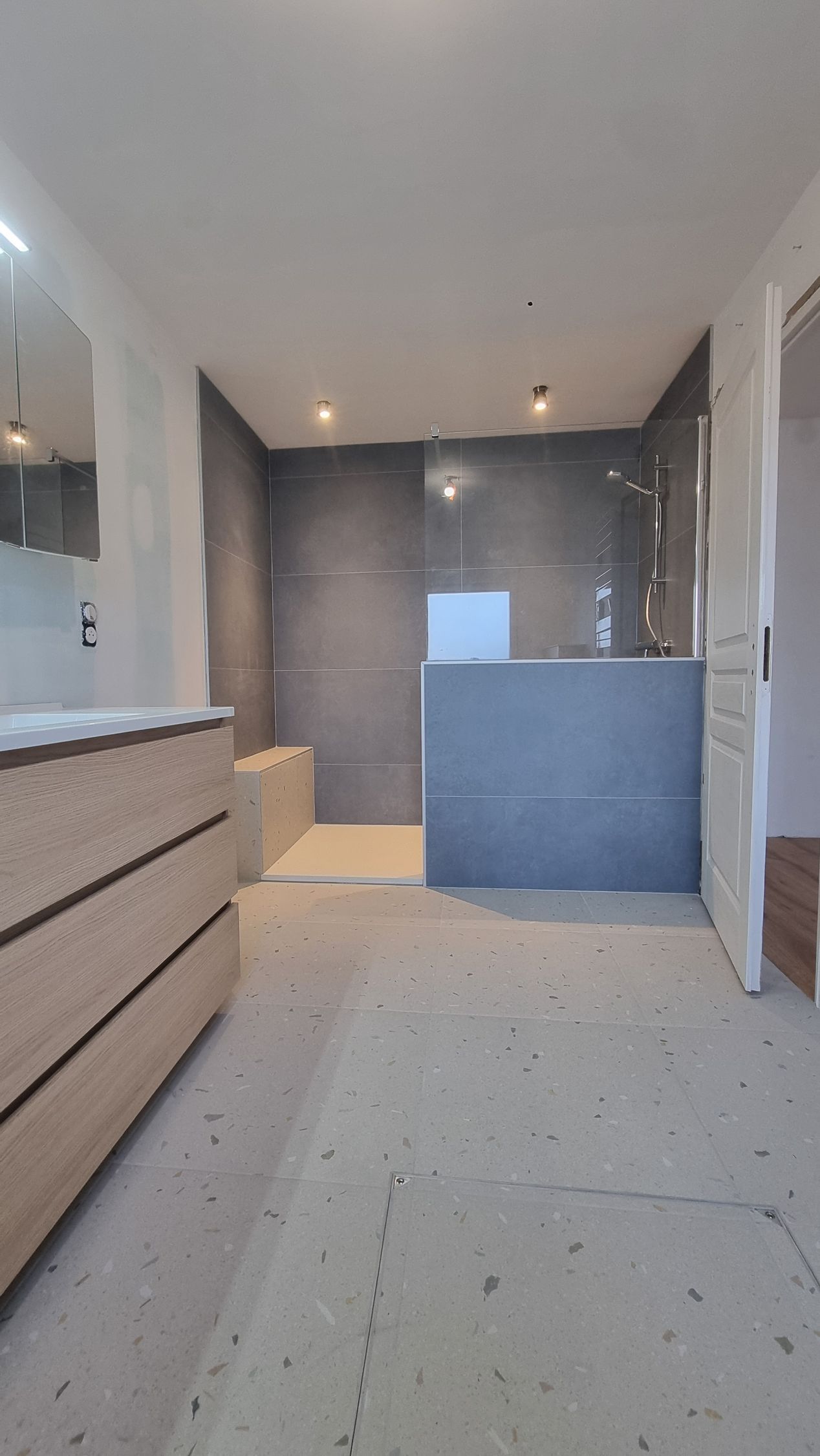 Intérieur de cuisine moderne avec armoires grises, îlot blanc et éclairage encastré au plafond