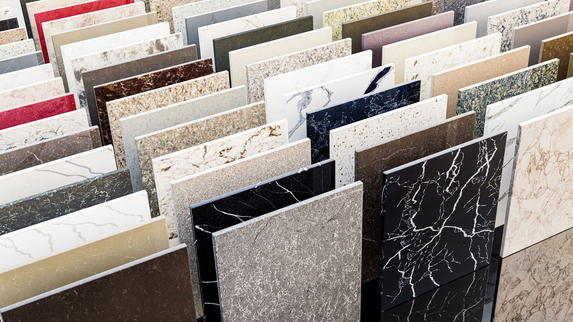 Des rangées d'échantillons de pierres ou de carreaux assortis, de couleurs neutres, présentés verticalement dans une salle d'exposition.