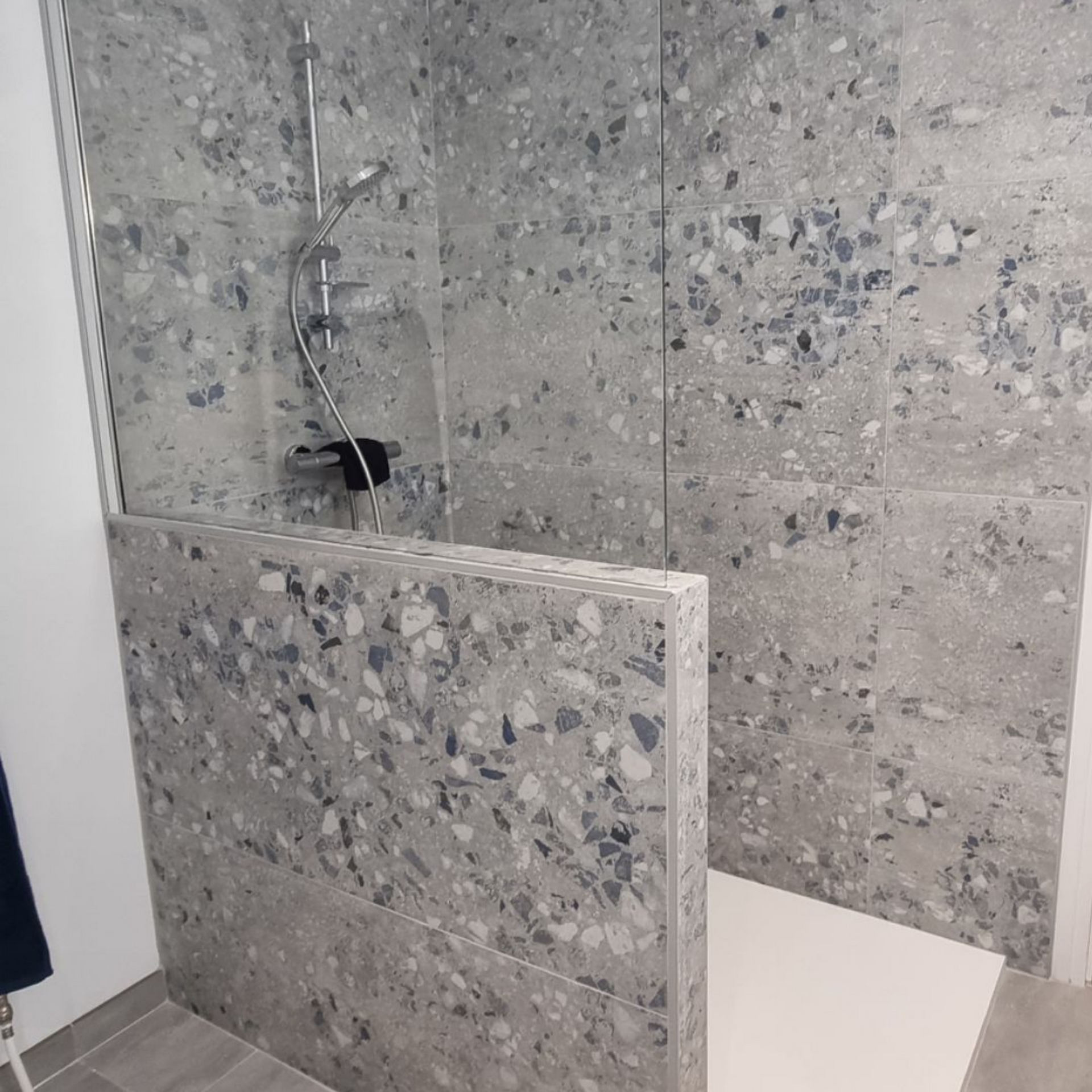 Douche carrelée avec paroi de douche en verre à mi-hauteur et robinetterie chromée intégrée
