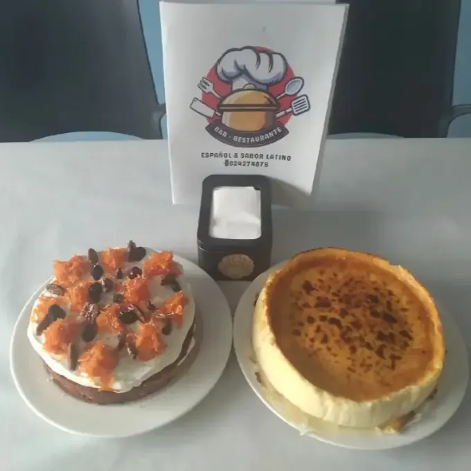 Dos pasteles decorados sobre platos blancos con un pequeño cartelito entre ellos.