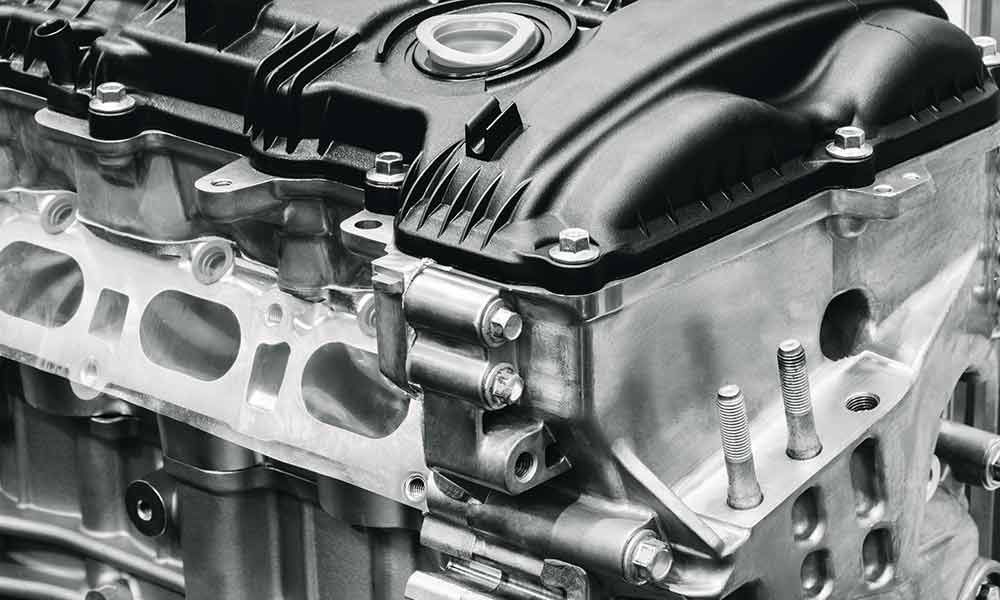 Motorblock mit schwarzem Ventildeckel und silbernen Schrauben.