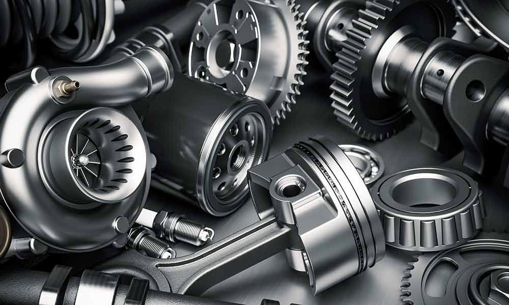 Ein Haufen glänzender, metallischer Autoteile, darunter Zahnräder, ein Kolben, ein Turbolader und Lager.