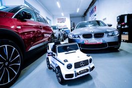 Zwei Männer geben sich im Hintergrund die Hand, links zwei Autohauben